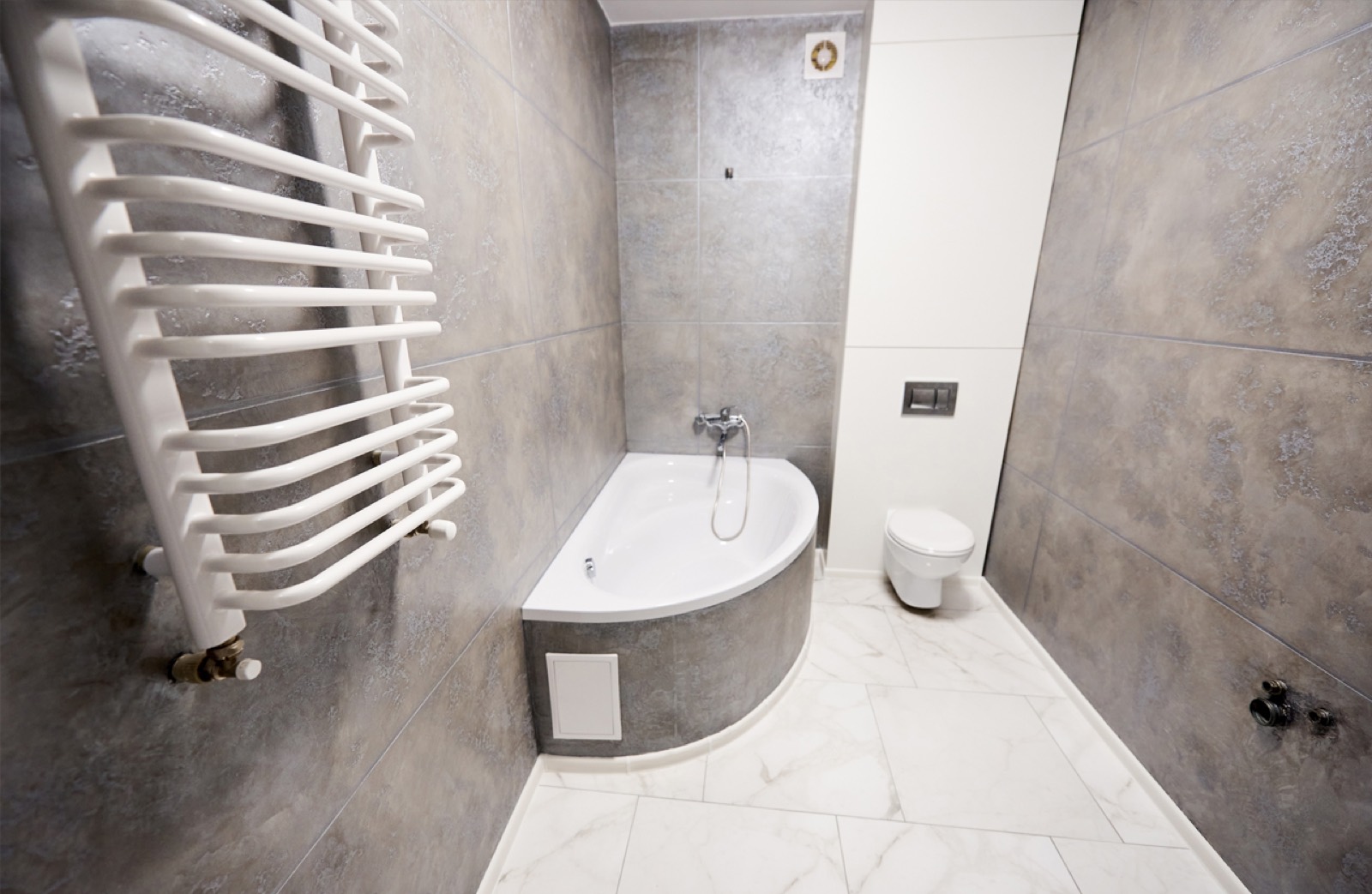 Fertiges Bad mit Eckbadewanne, Wand-WC und großformatigen Fliesen, nach der Sanierung