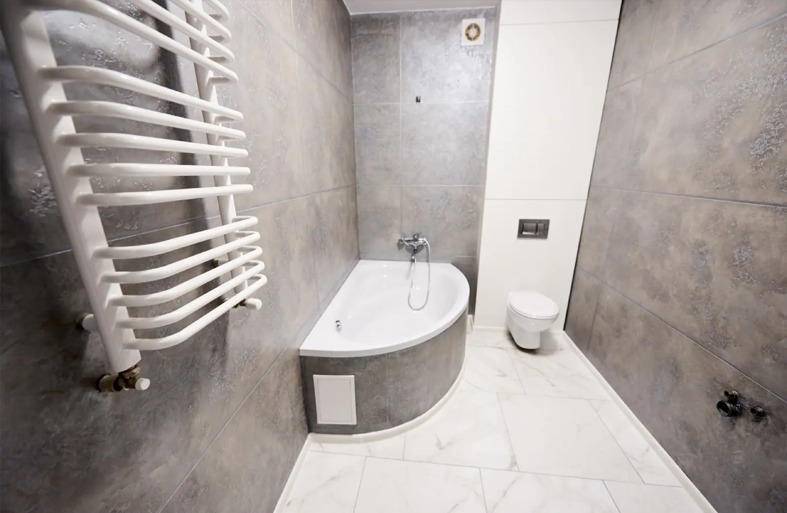 Fertiges Bad mit Eckbadewanne, Wand-WC und großformatigen Fliesen, nach der Sanierung