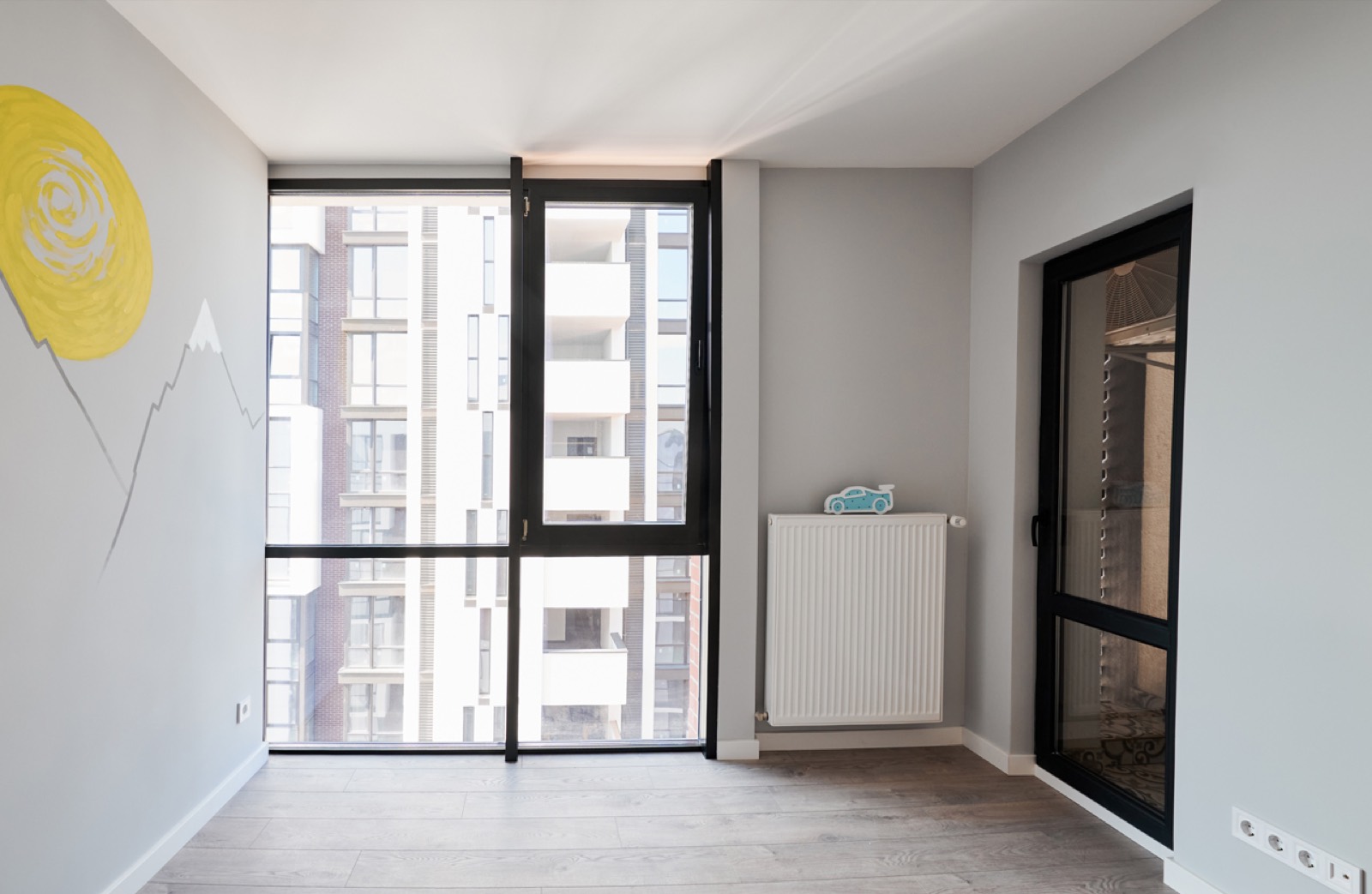 Fertig ausgebautes Zimmer mit gestrichenen Wänden, neuem Boden und Heizkörper, nach dem Ausbau