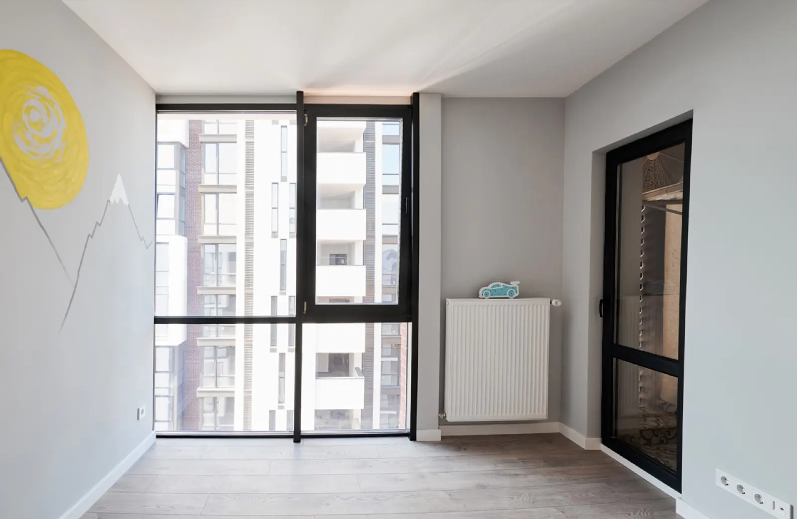 Fertig ausgebautes Zimmer mit gestrichenen Wänden, neuem Boden und Heizkörper, nach dem Ausbau
